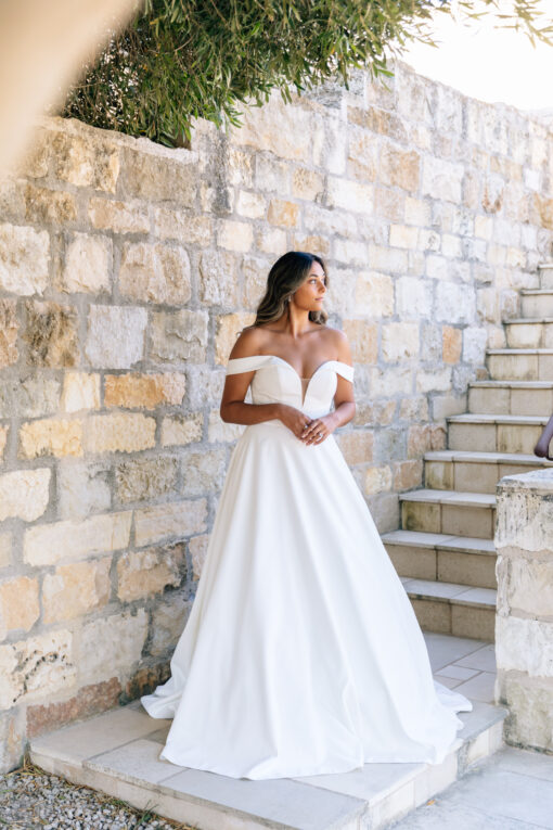 Essense of Australia wedding dress D2761: classic satin ballgown with plunging sweetheart neckline, off‑the‑shoulder straps, fitted waist, full skirt with pockets and button‑back train.