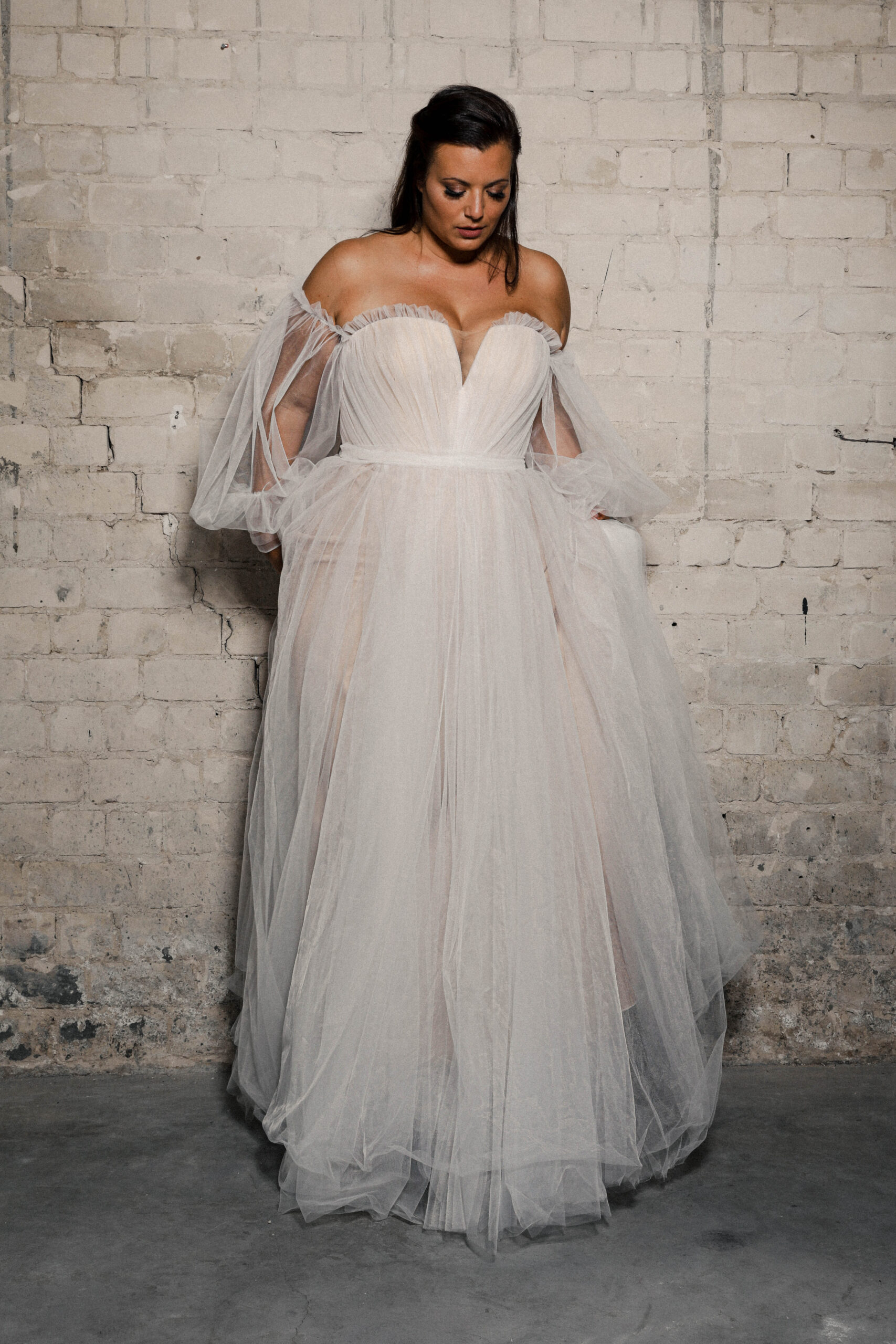 Tamia wedding dress by Studio Levana featuring a sheer layered ball gown skirt, sweetheart neckline, structured corset bodice, and detachable sleeves
