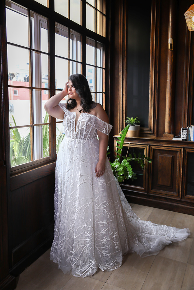 Tasha wedding dress by Studio Levana featuring a sheer corset bodice, off-the-shoulder sleeves, and a beaded sparkly tulle ball gown skirt